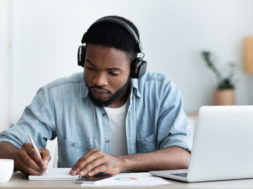 Serious african american student in headphones studying foreign language online