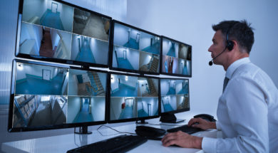 Security System Operator Looking At CCTV Footage At Desk