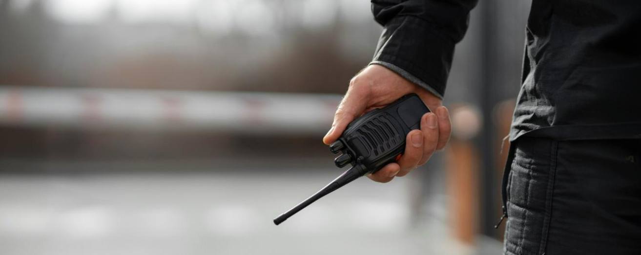 Close-up of a security professional holding a two-way radio, symbolizing vigilance and readiness in the field.