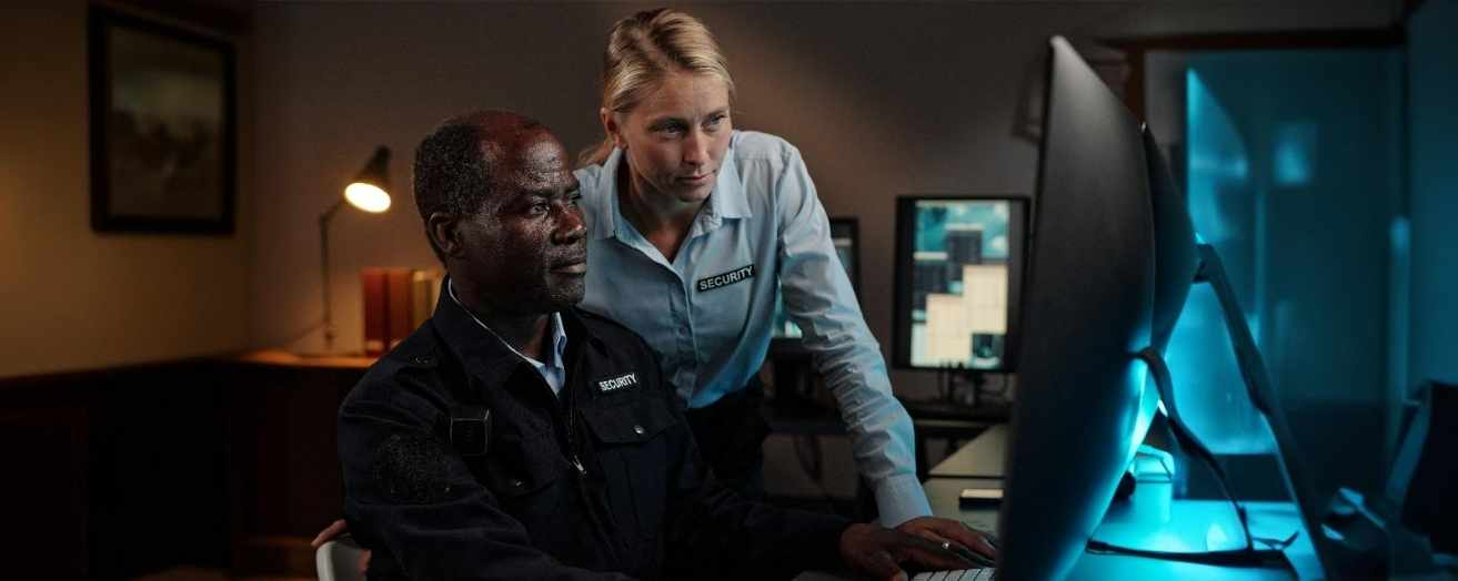 Security manager supervising an officer in a control room – a key non-frontline security role.