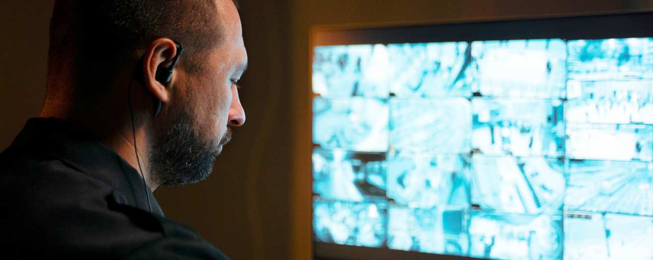 A security officer monitoring multiple CCTV screens, ensuring safety and surveillance at a high-profile event.