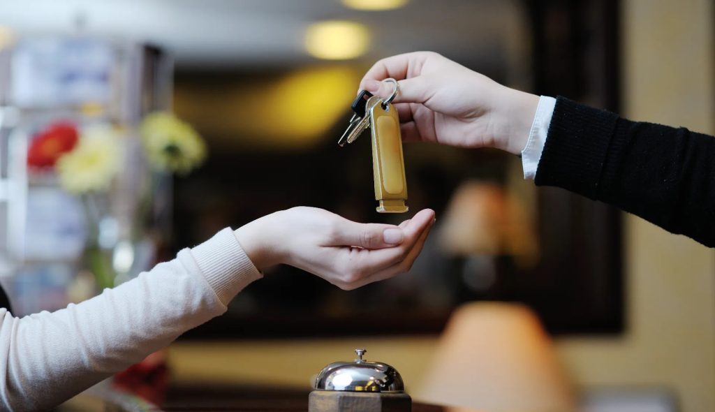 Hotel receptionist handing room key to guest at check-in desk