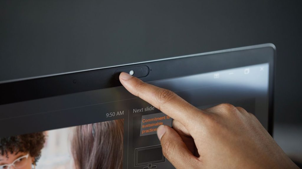 Person covering laptop camera to ensure privacy in a hotel room.