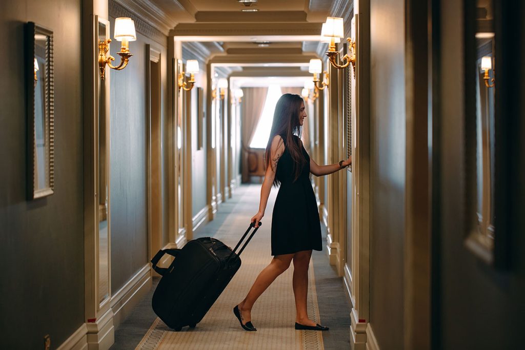 Female guest walking in a well-lit hotel corridor, emphasizing safe and secure hotel environment