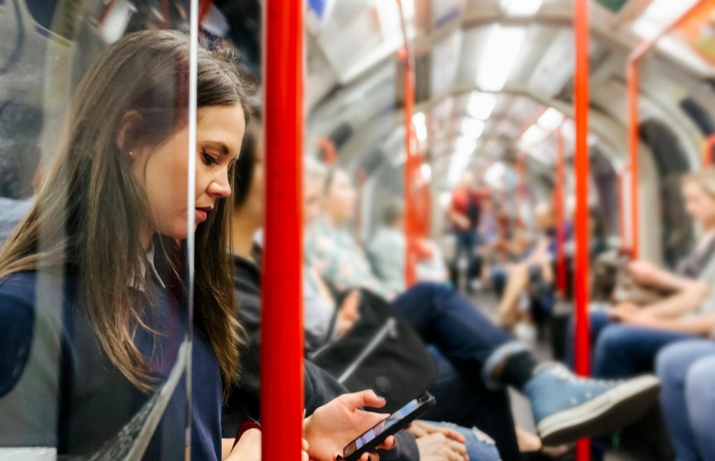 Passenger sitting on the Tube, distracted by her phone