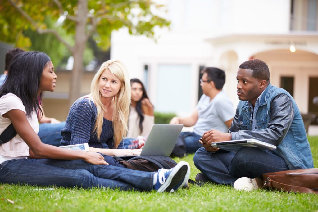 International students engaged in a discussion on campus, reflecting a vibrant and collaborative university environment in the UK.