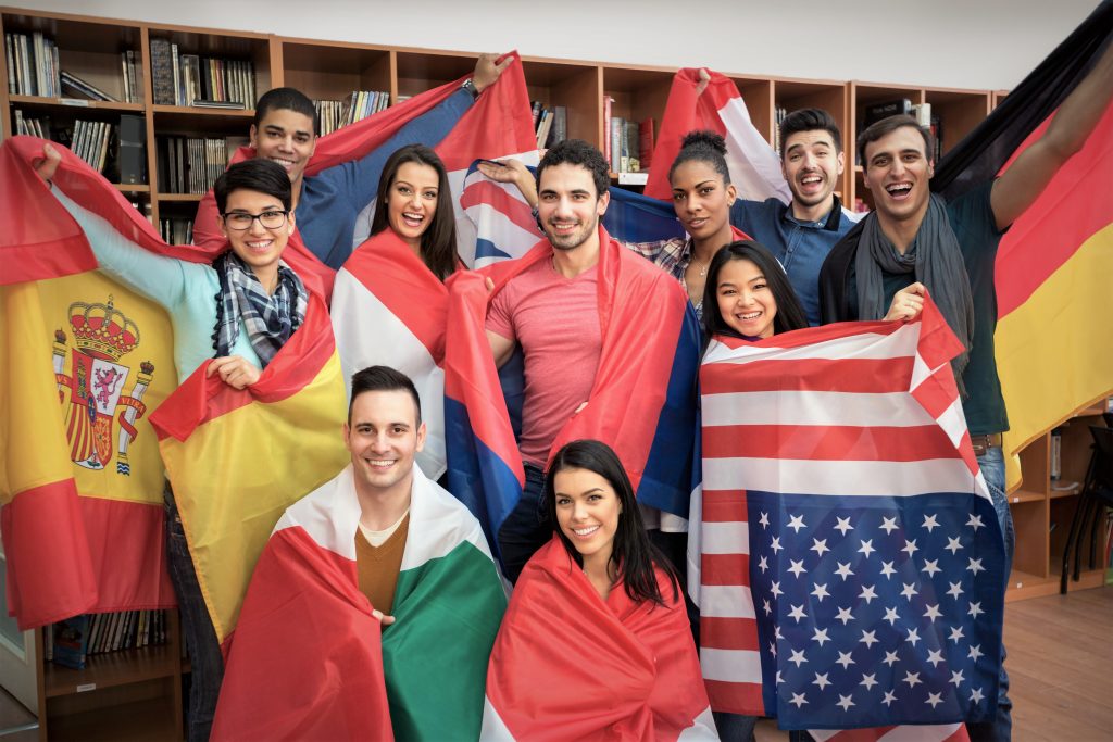 Group of international students holding their country’s flags, celebrating diversity and unity in the UK.