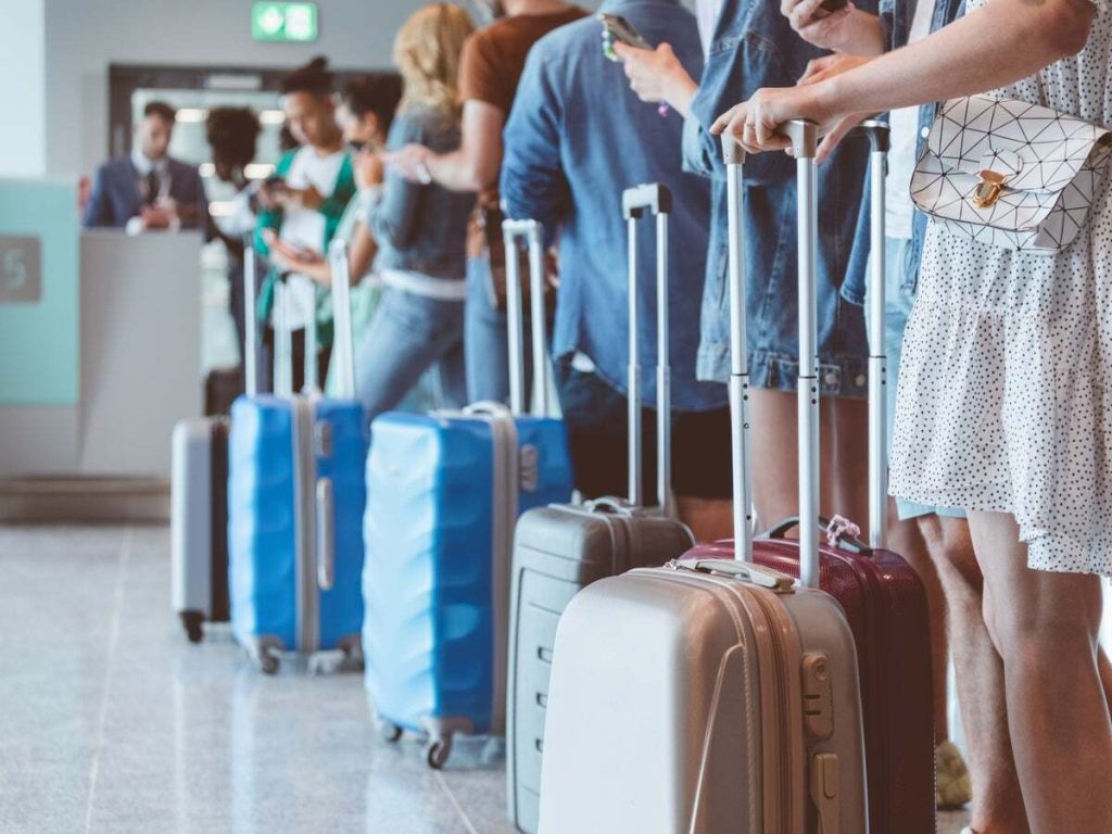 A queue of passengers with their luggage at the airport entrance