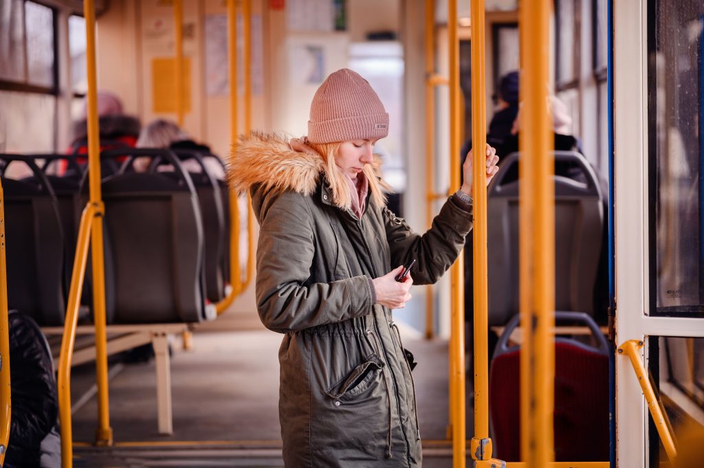 Woman in winter clothing standing inside a train in the UK.