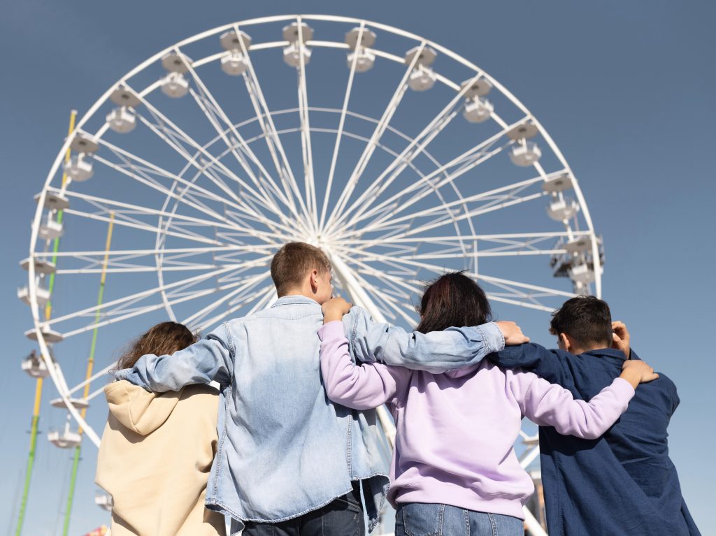 A group of friends standing in front of a ferris wheel.