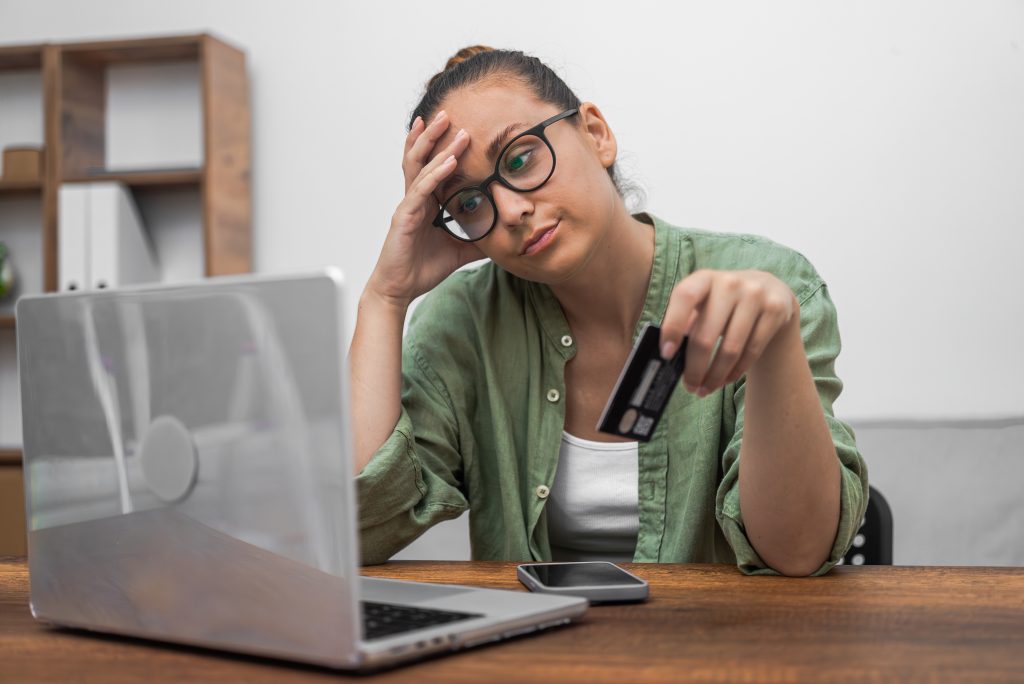 A stressed woman gazes at her laptop screen, visibly upset by having been scammed online.